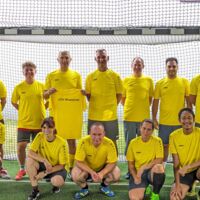 Mannschaftsfoto des Teams beim Präses-Cup. Die Spieler*innen tragen gelbe Trikots und haben sich im Tor aufgestellt. 5 Personen hocken in der ersten Reihe und dahinter stehen 7 Personen.